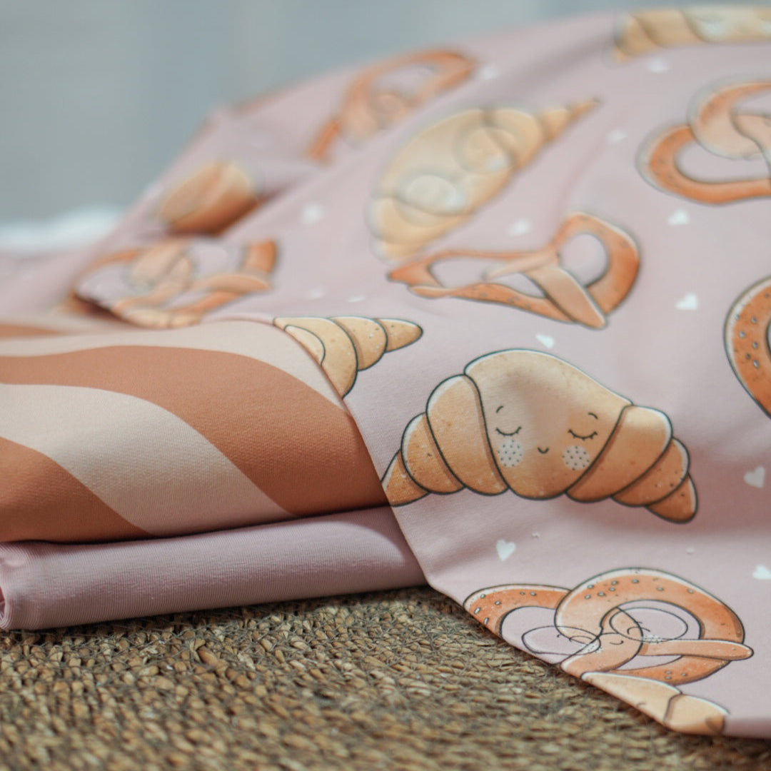 Kinderstoffe Meterware süße Brezel und Croissant mit Gesicht und Brille von Katzengold Design