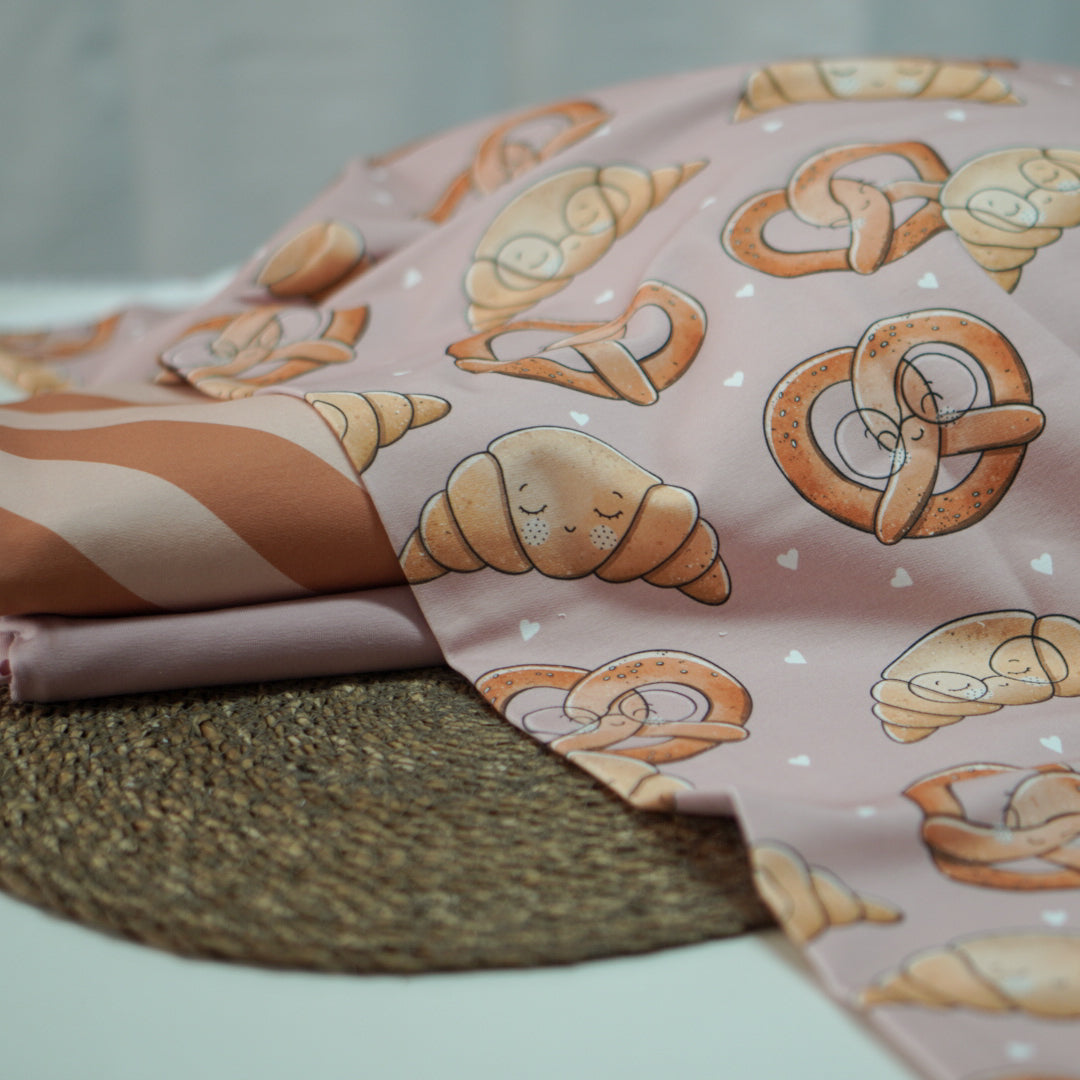 Kinderstoffe Meterware süße Brezel und Croissant mit Gesicht und Brille von Katzengold Design