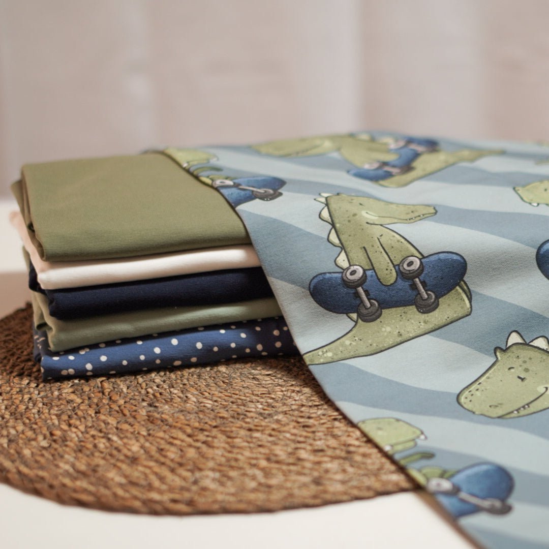 Kinderstoff Jungsstoff T-Rex Dino mit Skateboard auf blauen Streifen von Katzengold design Kombistoffe